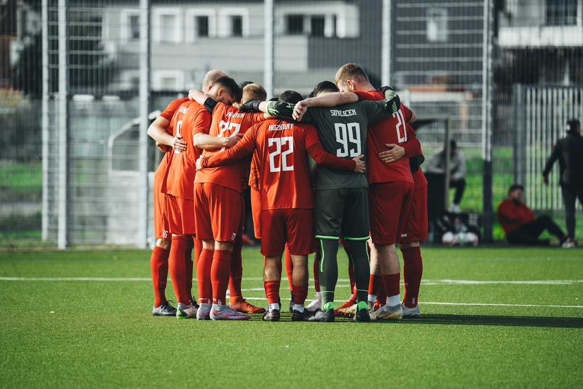 A group of soccer players huddle together on the field