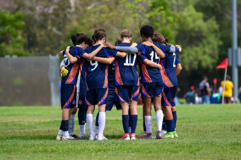 A soccer team huddles together on a green field.